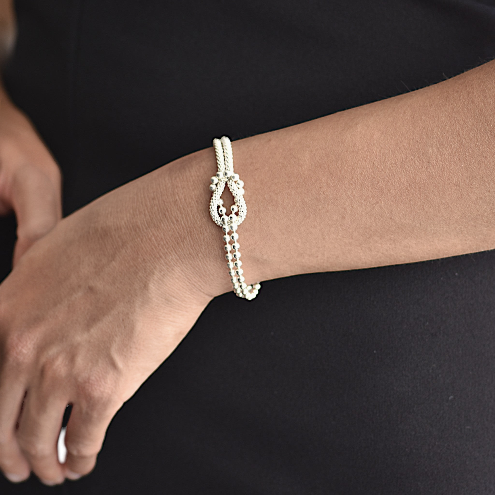 Amara Jewels sterling silver bracelet with multi-strand design and knot centerpiece, featuring polished silver beads.