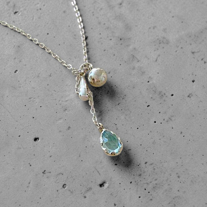 Amara Jewels sterling silver necklace with a blue teardrop gemstone pendant and silver charms.