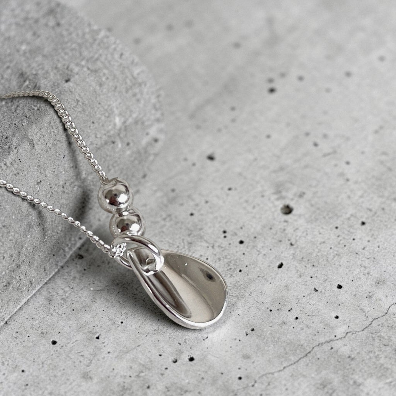 Amara Jewels polished sterling silver teardrop pendant necklace with two accent beads on a delicate chain.