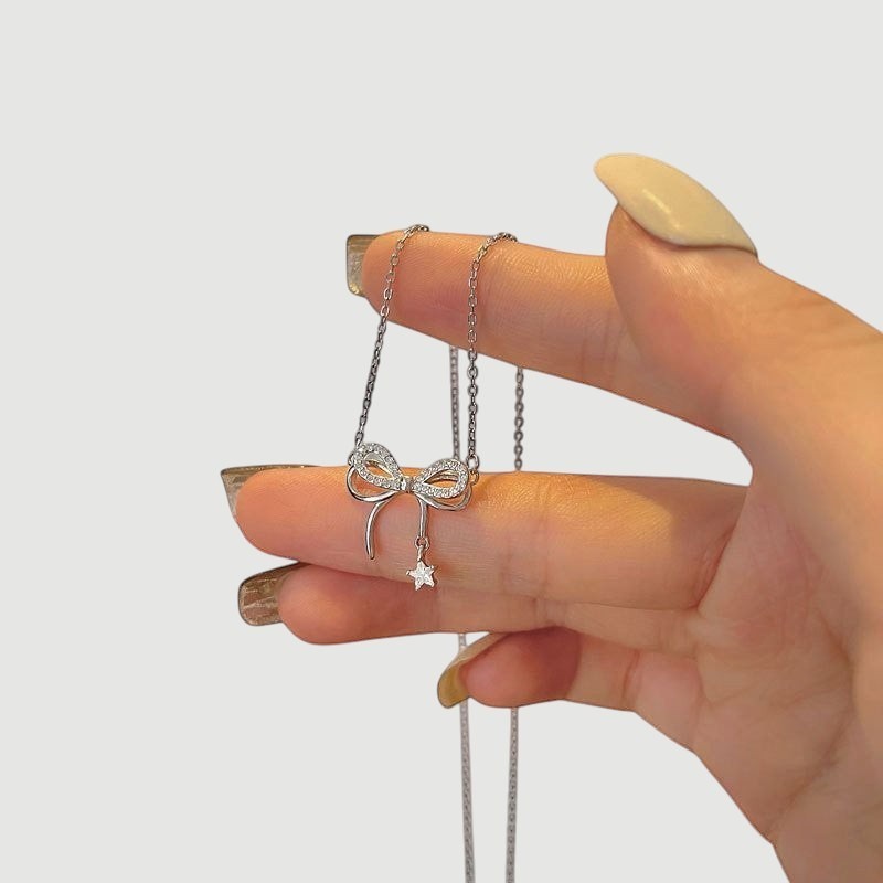 Amara Jewels sterling silver necklace with a sparkling bow charm and dangling star pendant.