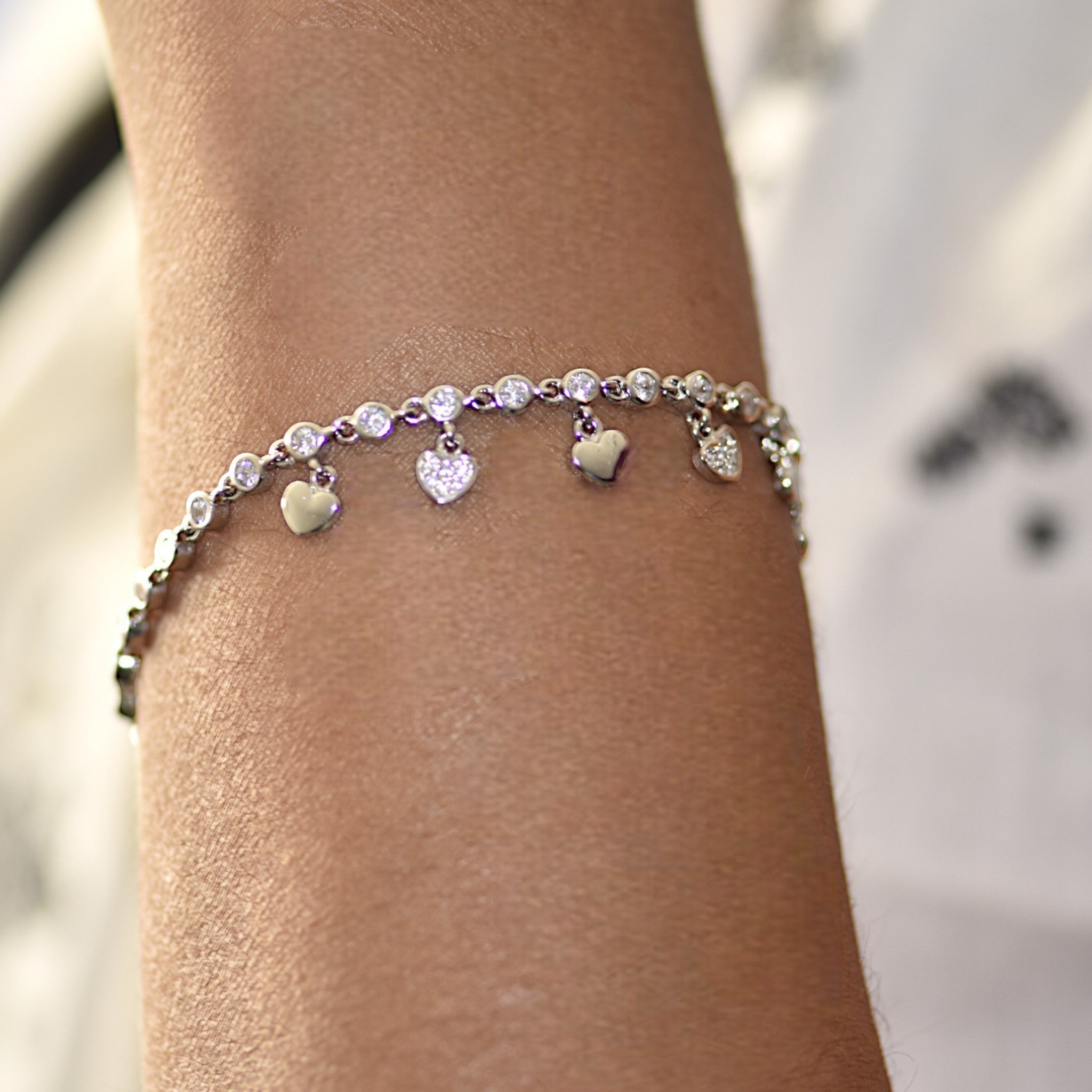 Amara Jewels sterling silver bracelet with cubic zirconia stones and dangling heart charms.