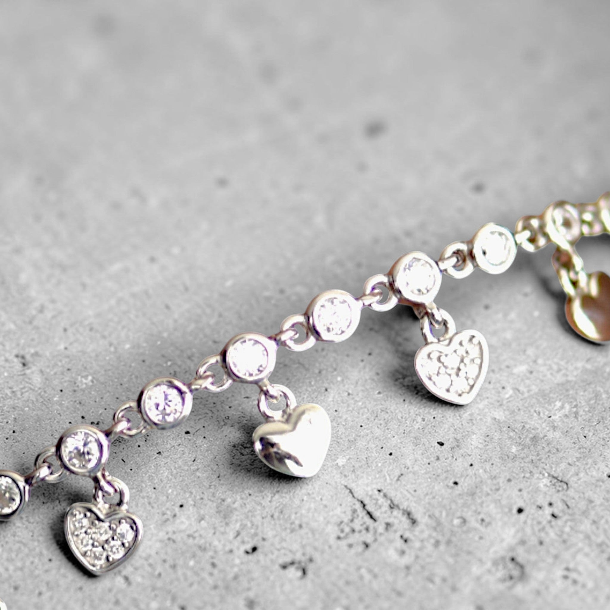 Amara Jewels sterling silver bracelet with cubic zirconia stones and dangling heart charms.