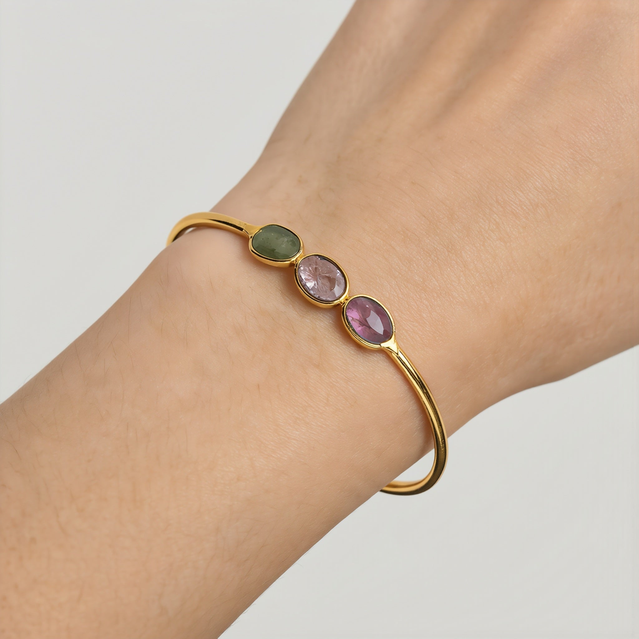 Amara Jewels 18K gold vermeil wrap bracelet with three bezel-set oval tourmaline gemstones in pink, green, and red.