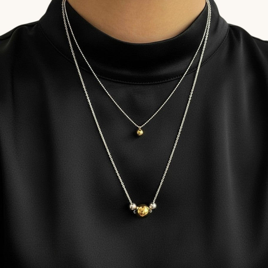 Amara Jewels two-tone sphere pendant necklace with polished silver chain, featuring a large gold sphere and a smaller silver sphere.